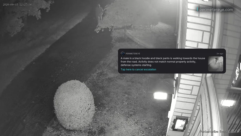 Infrared camera view of a person walking up the driveway, with the PerimeterEye alert describing them
